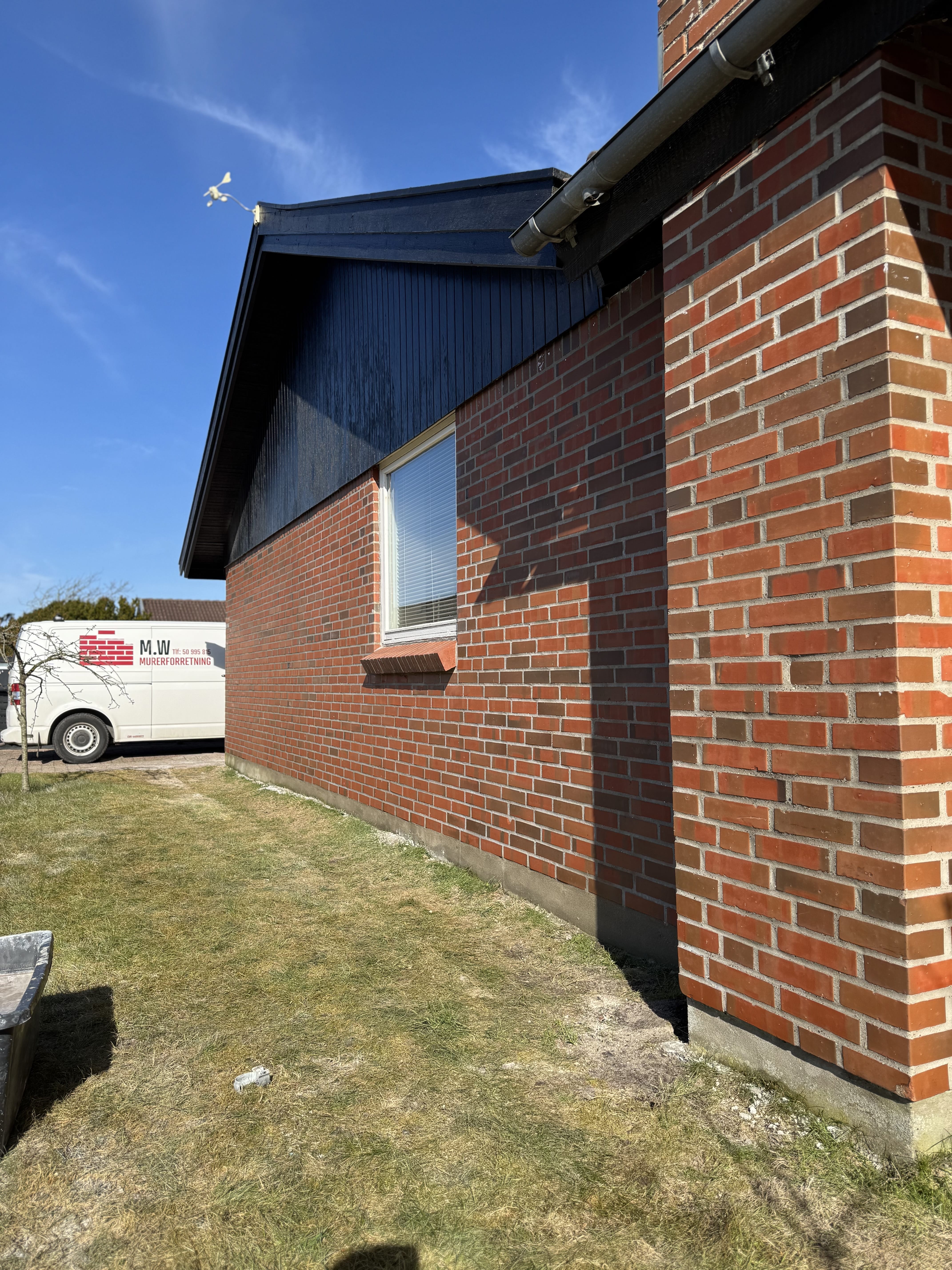 Murermesterarbejde på rødt murstenshus i solskin